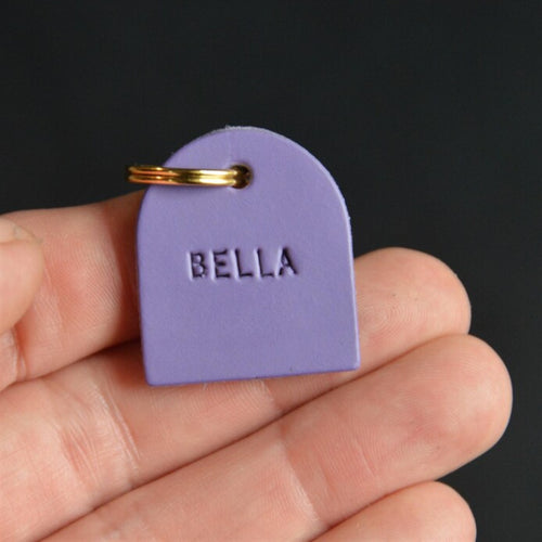 Purple name charm embossed BELLA held in hand